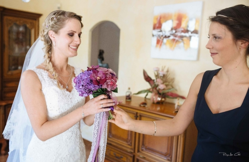 Anecdotes, une wedding planner qui remet le bouquet violet à la mariée en robe de mariée