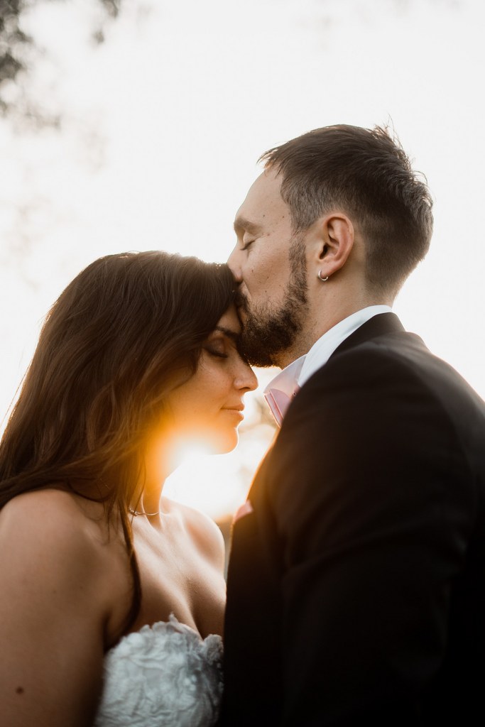 2022 Un marié qui embrasse la mariée sur le front au coucher du soleil