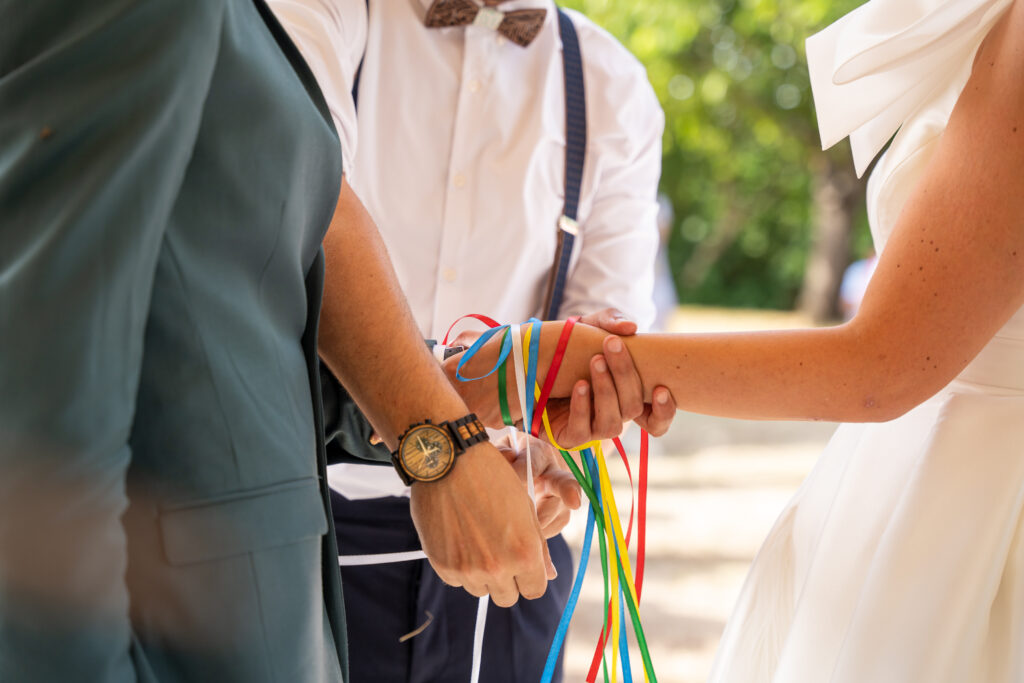 Rituel cérémonie les mariés se tiennent par la main et le témoin vient nouer les rubans autour des poignets des mariés