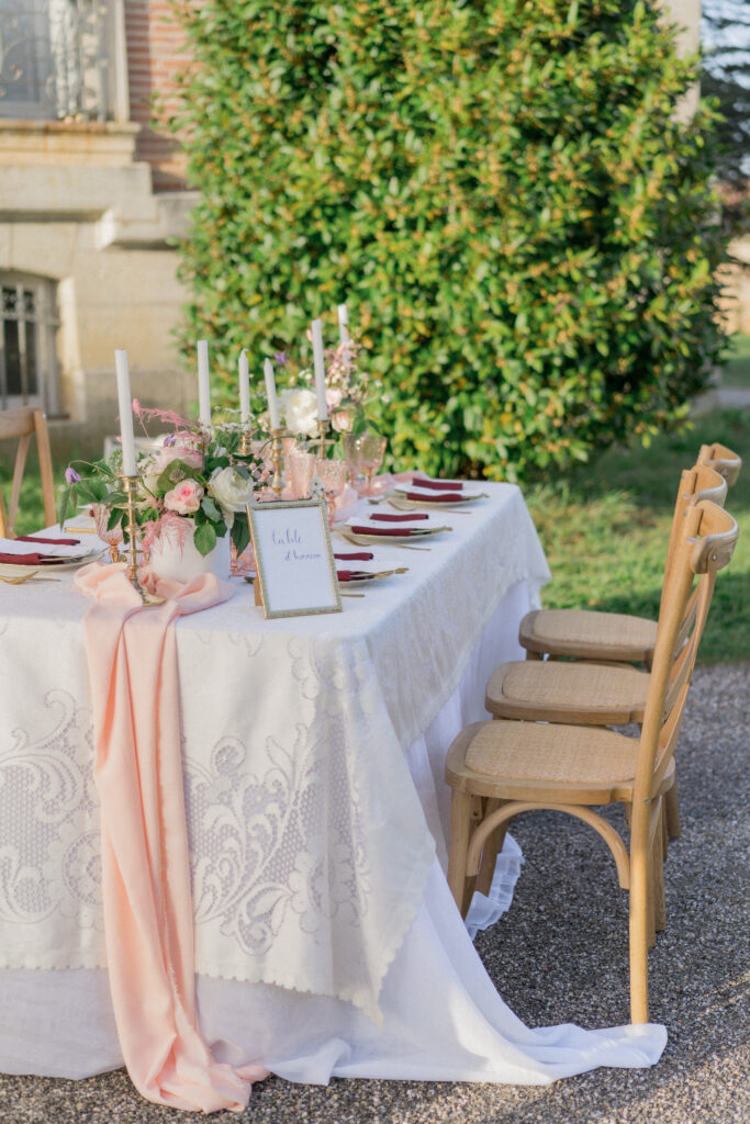 Salon du mariage : table de mariage avec un centre de table rose poudré des chaises croisillon des chandeliers dorés