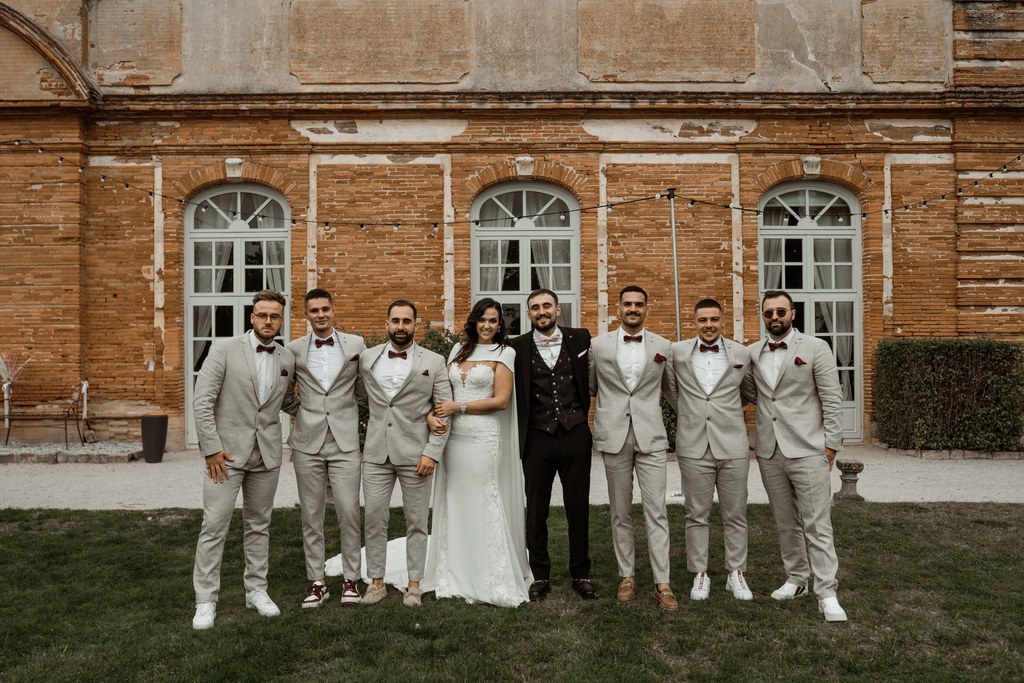 Cortège mariage photo de groupe des mariés avec les garçons d'honneur en beige et bordeaux alignés