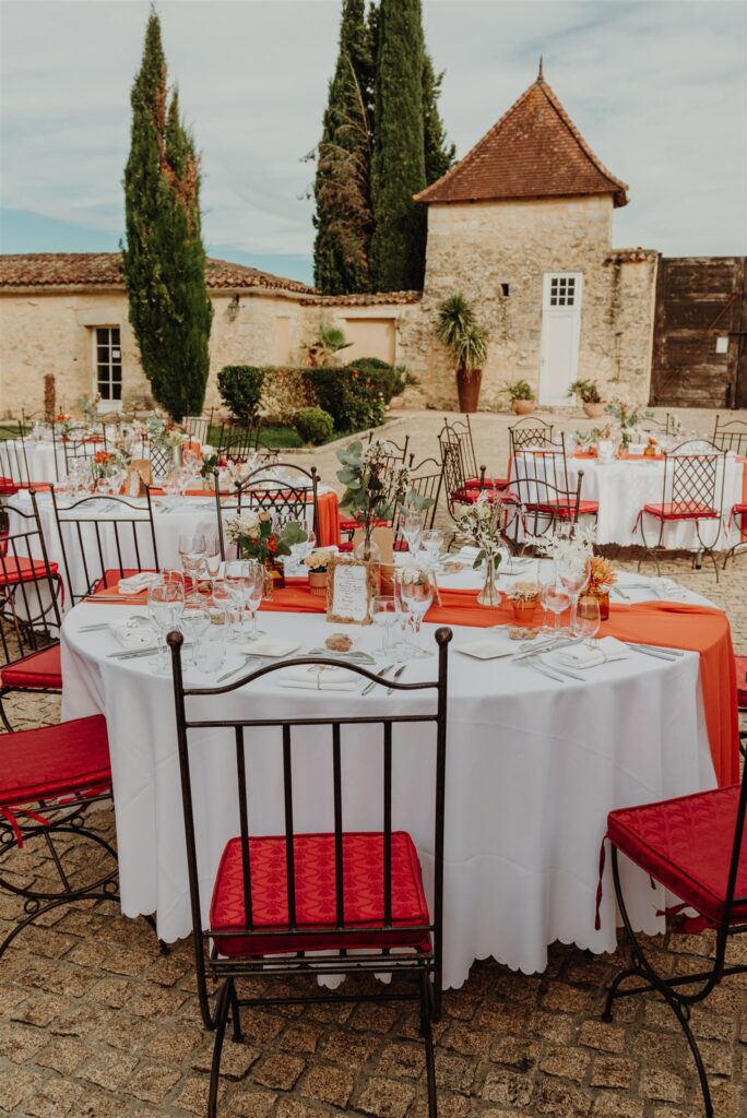 Tables d'un mariage dressées dans la cours d'un château, aux couleurs terra cotta