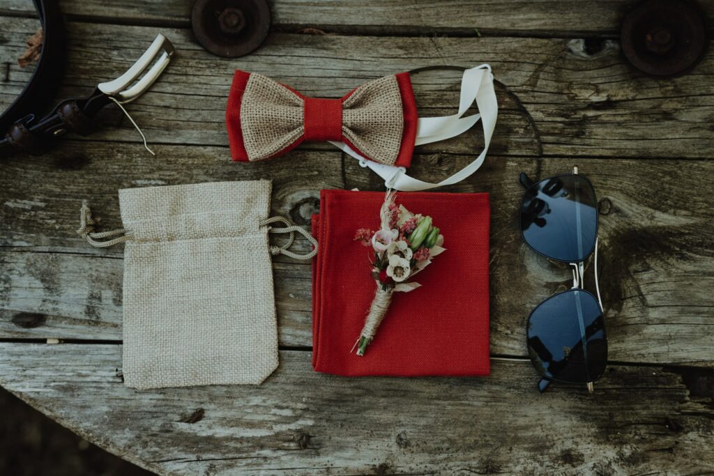 témoin de mariage : lunette de soleil, boutonnière, noeud papillon posées sur un banc