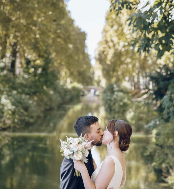 Des mariés qui s'embrassent devant le canal du midi le jour de leur mariage