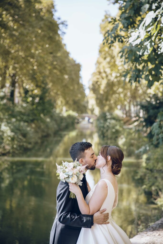 Les mariés s'embrassent devant le canal du midi.