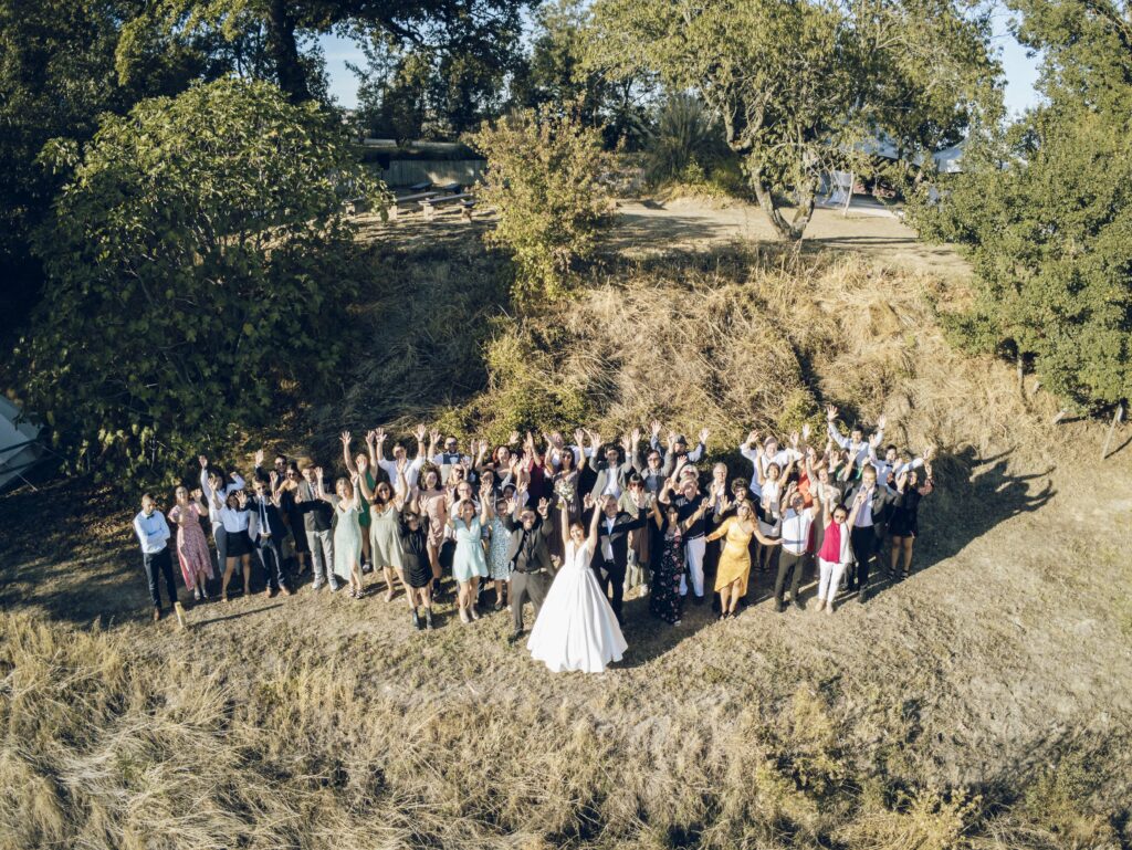 Photo de groupe à un mariage les mains levées, dans un champ
