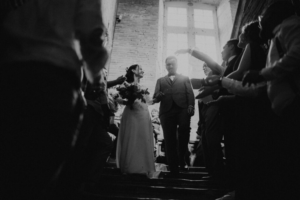 Officiante de cérémonie laïque faisant sortir un couple de mariés de leur cérémonie descendant les escaliers sous les applaudissement