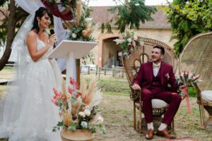 Voeux une mariée prononçant ses voeux devant son mari en costume rouge et elle en robe blanche. elle est debout lui assis